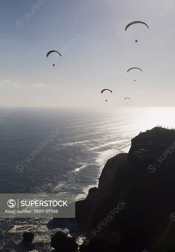 Paragliders soar free over the cliffs of the Bukit Peninsula in Bali, Indonesia