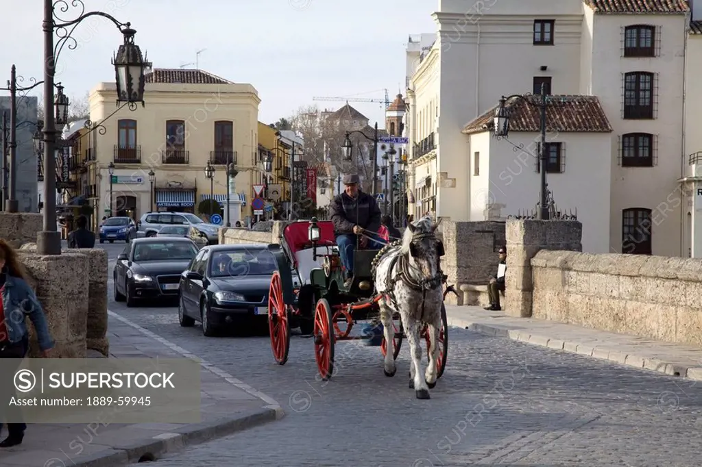 Ronda, Andalusia, Spain, A Horse And Carriage Followed By Cars Going Over The Bridge