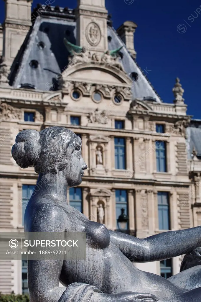 statue of a lady reclining with a building of french architecture in the background, paris, france