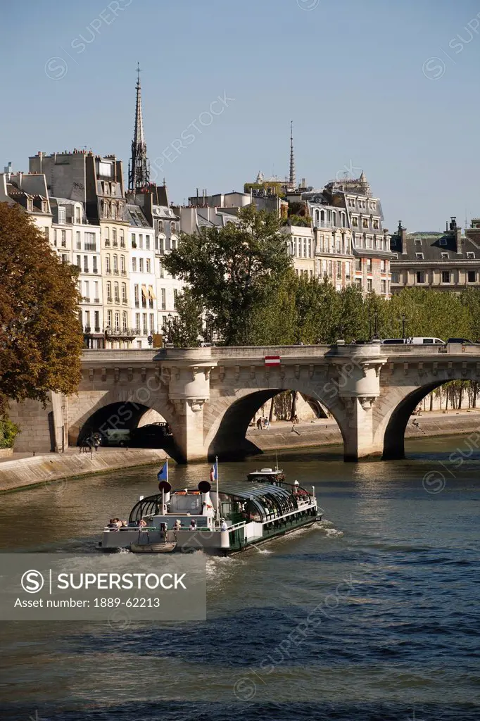 tour boat along the river with bridge and building in the background, paris, france