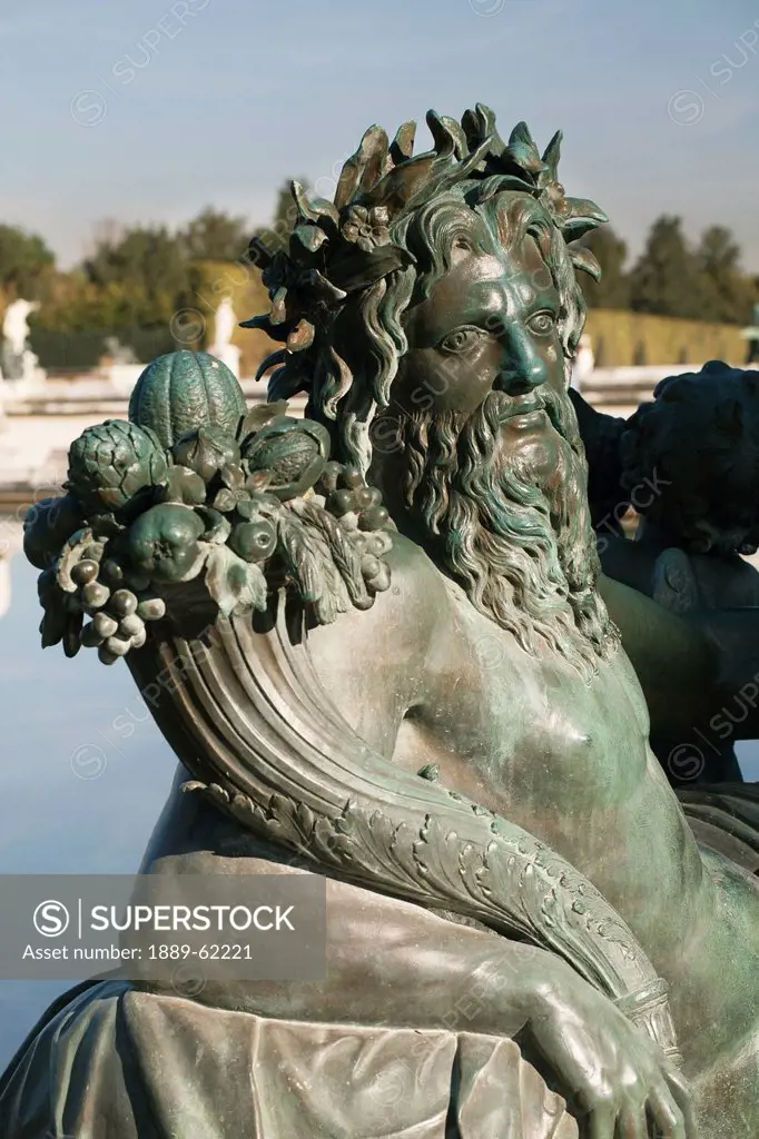 statue of a man holding a cornucopia filled with food along a pool, paris, france