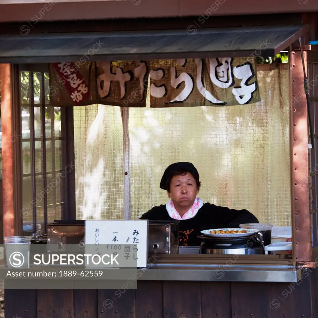 a woman selling food behind a counter at the todaiji temple, nara, japan