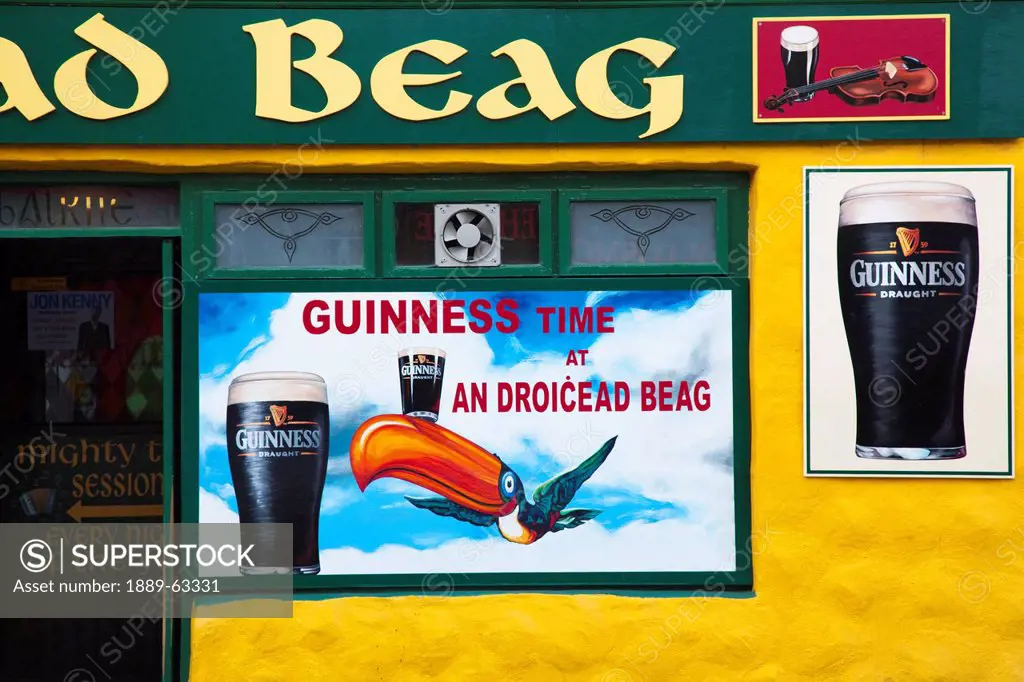 exterior of pub with signs depicting guinness ale, dingle, county kerry, ireland