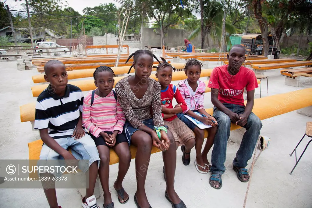 a group of children and teenagers sitting in a row on a bench, port_au_prince, haiti