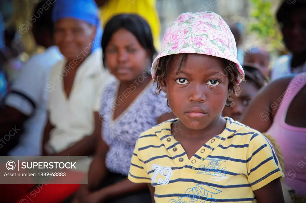 a girl with a sad face and women sitting behind her in the hope alive clinic, grand saline, haiti