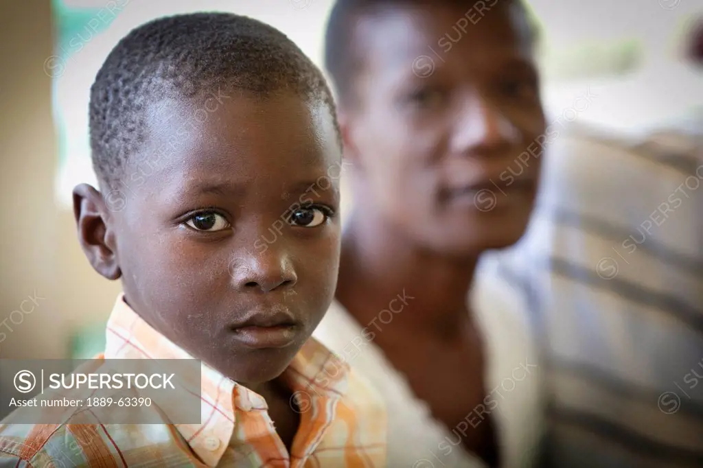 a boy sitting beside his father, grand saline, haiti