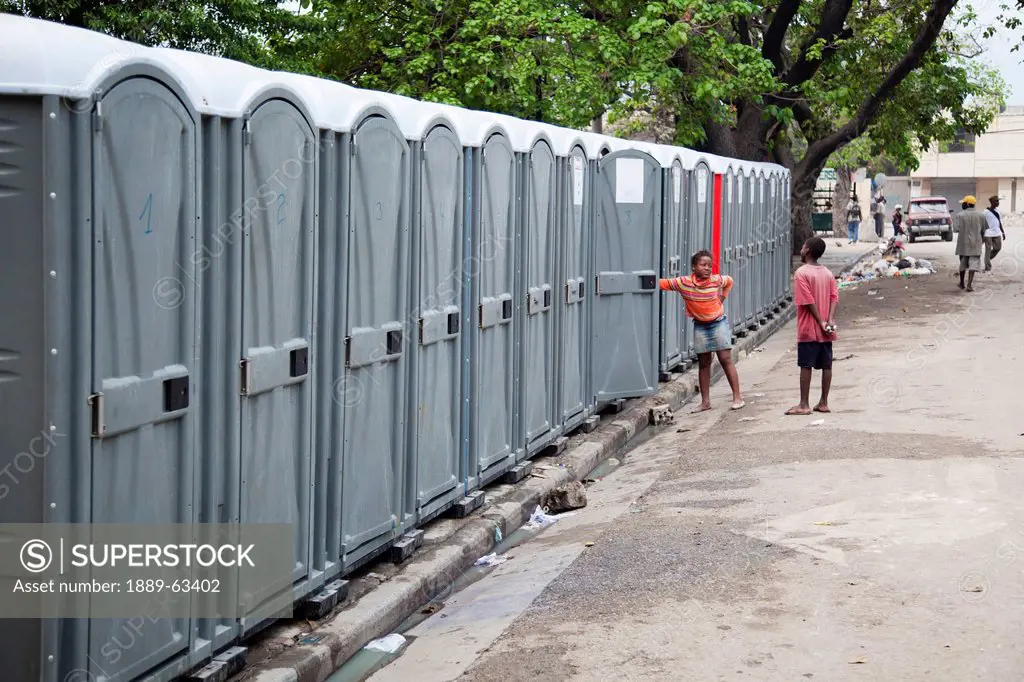 two children standing by a row of portable toilets, port_au_prince, haiti