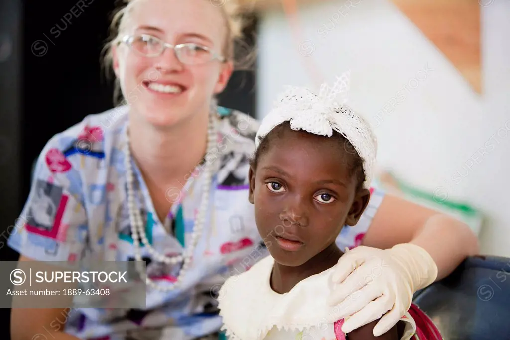 a nurse sits with a girl at a clinic, grand saline, haiti