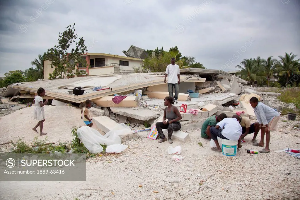 a family sits amidst the rubble of their home, port_au_prince, haiti