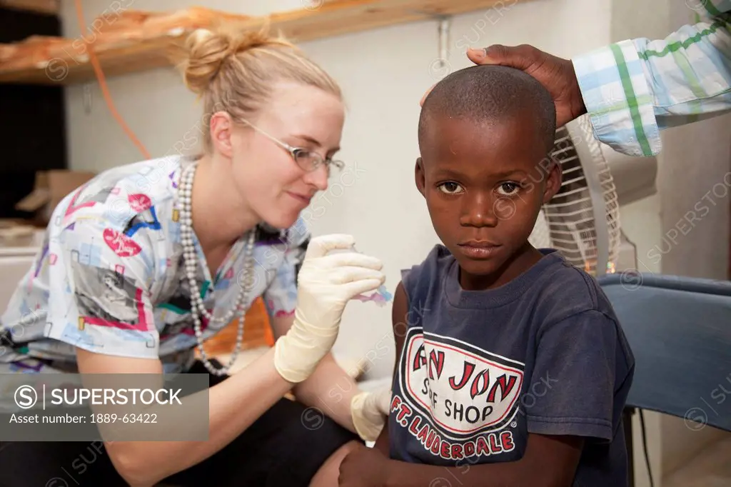 a nurse gives a vaccination to a boy, grand saline, haiti