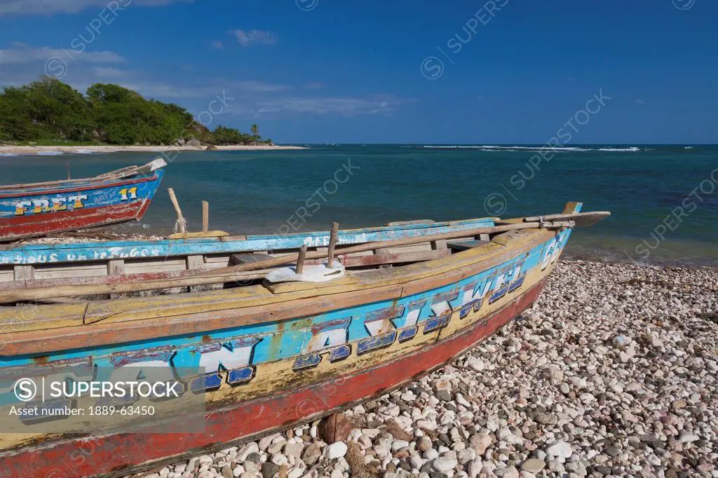 old wooden boats sitting on the rocky shore, jacmel, haiti