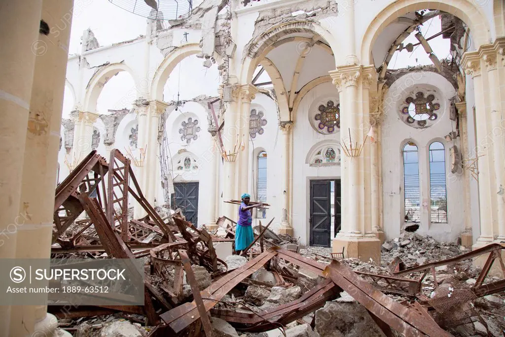 a woman carries out pieces of wood from the destroyed catholic cathedral of our lady of the assumption, port_au_prince, haiti