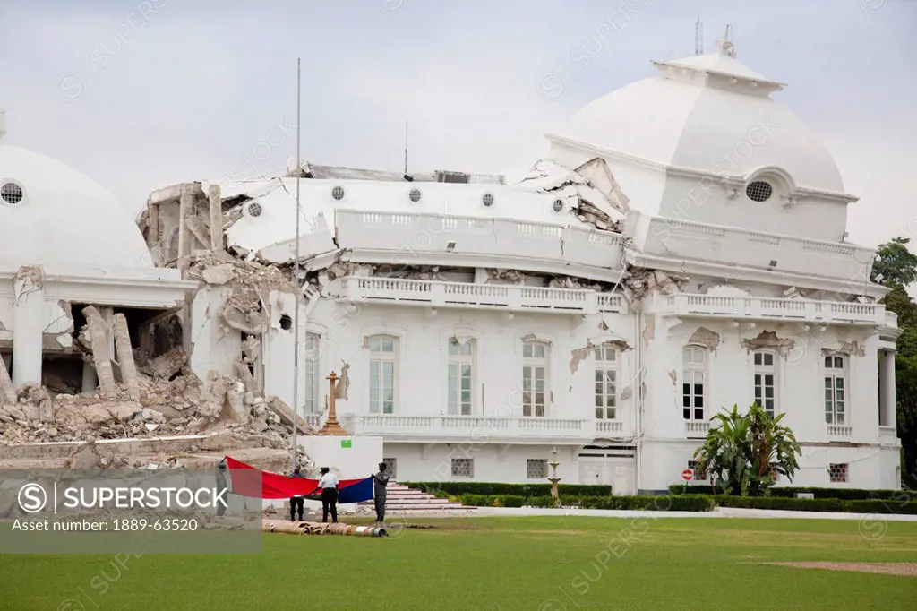 the presidential palace government building leans and is collapsed and the flag is being removed from the pole after the earthquake, port_au_prince, h...