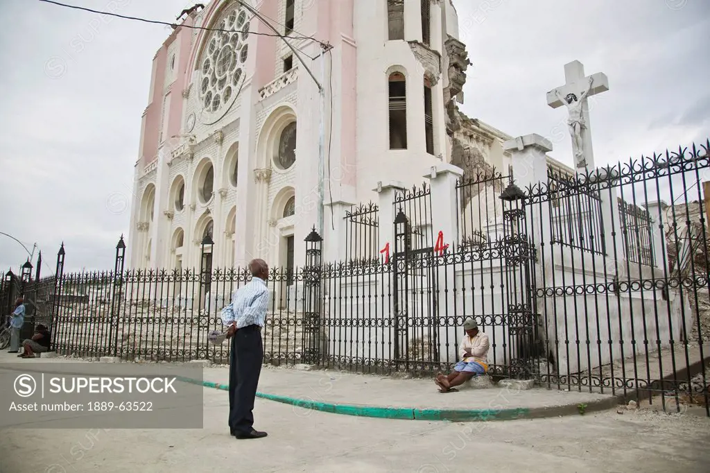 the cross still stands through the church being destroyed in the earthquake as the parishioners still come to seek god for answers and consolation, po...