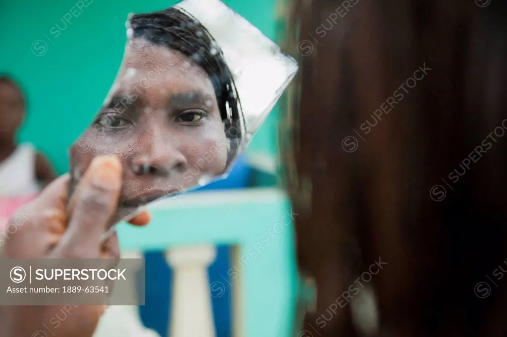 a survivor of an earthquake looks into a broken mirror with a face of despair, pierre payen, haiti