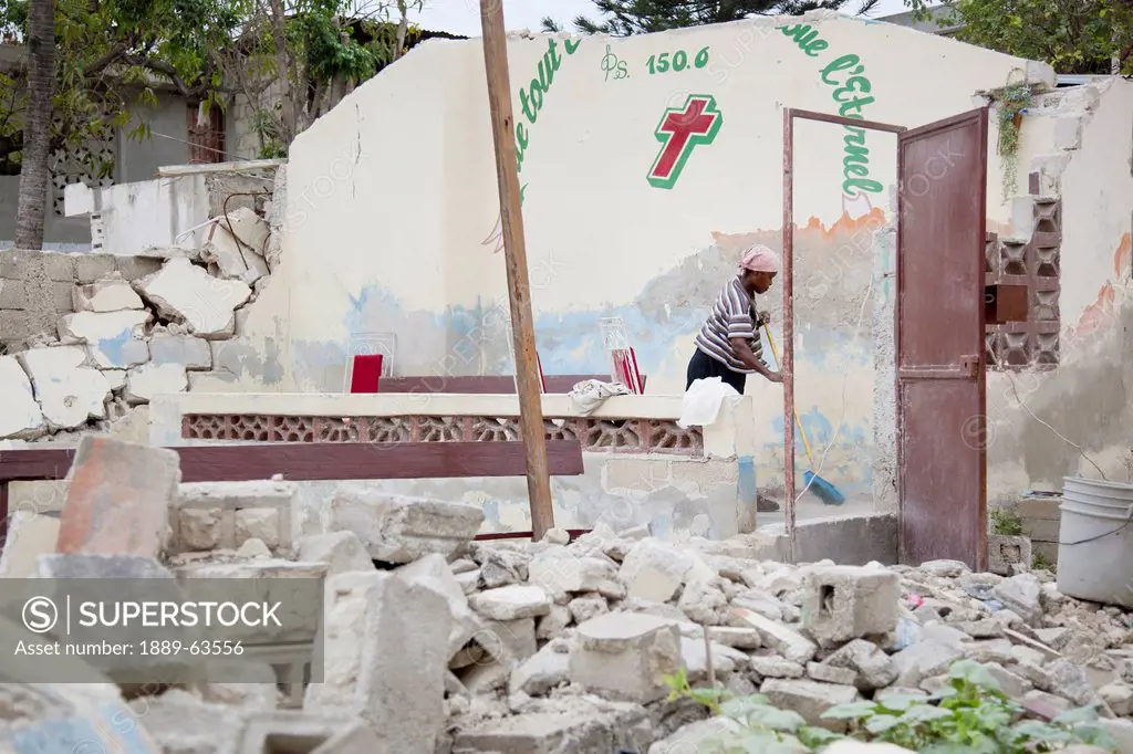 a woman cleans up around the rubble of a destroyed church building after the earthquake, port_au_prince, haiti