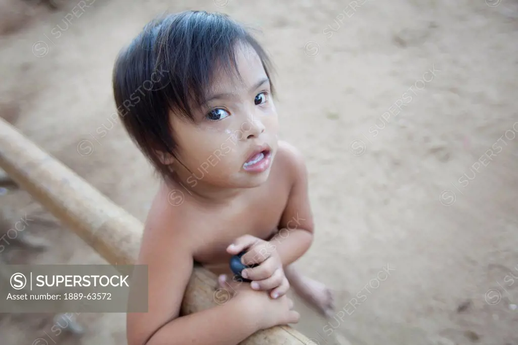 a young girl with down syndrome stands in the dirt in a poor area, el nido, bacuit archipelago, palawan, philippines