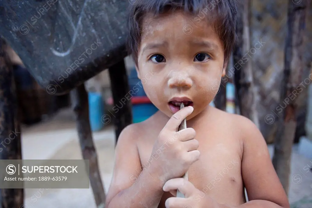 a young boy with no shirt stands in the village, el nido, bacuit archipelago, palawan, philippines