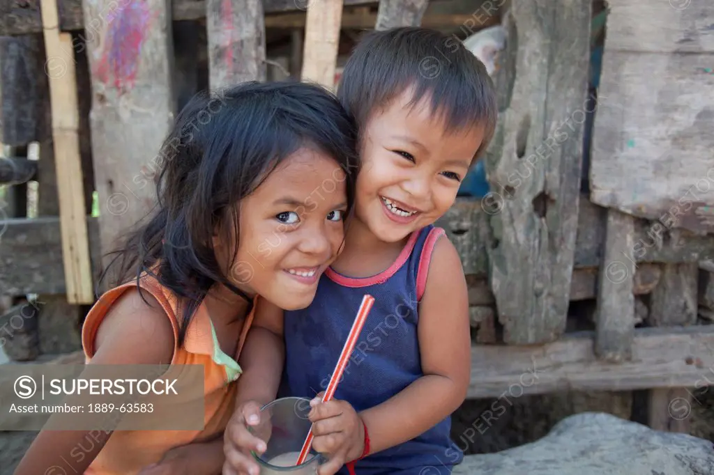 a young girl and boy drink a glass of milk, corong corong, bacuit archipelago, palawan, philippines