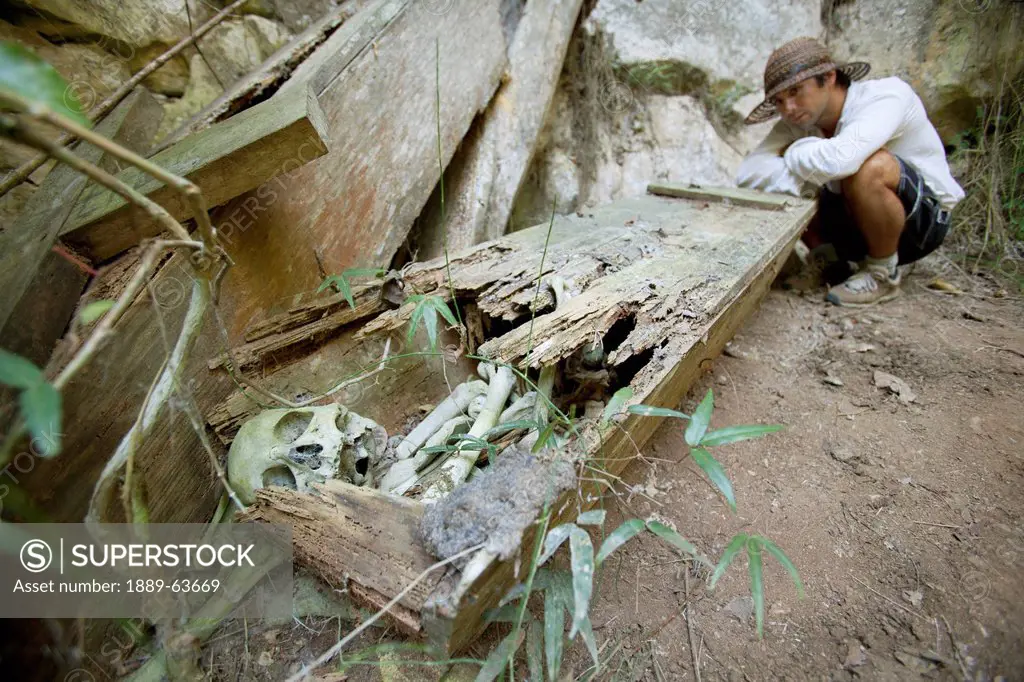 a male tourist examines an old coffin with the skeletal human remains intact, that was once hanging high on a cliff, near mountain village of sagada, ...