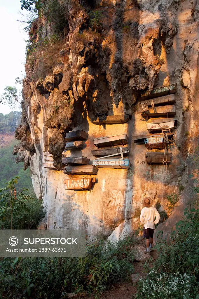 a male tourist looks up at the famous hanging coffins resting high on the limestone cliffs in echo valley near the mountain village of sagada, in the ...