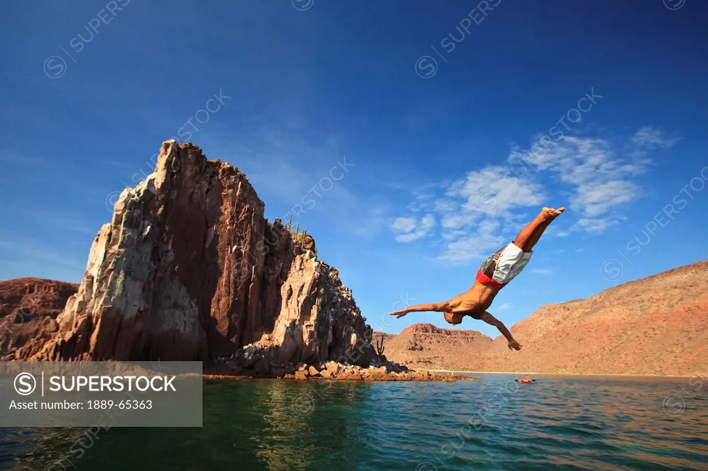 a man dives into the water off espiritu santos island near la paz, baja california mexico