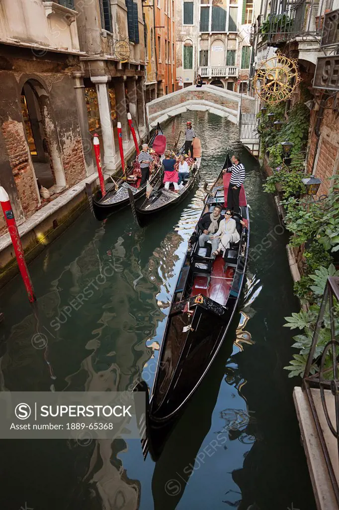 gondoliers give rides to passengers in gondolas in the grand canal, venice italy