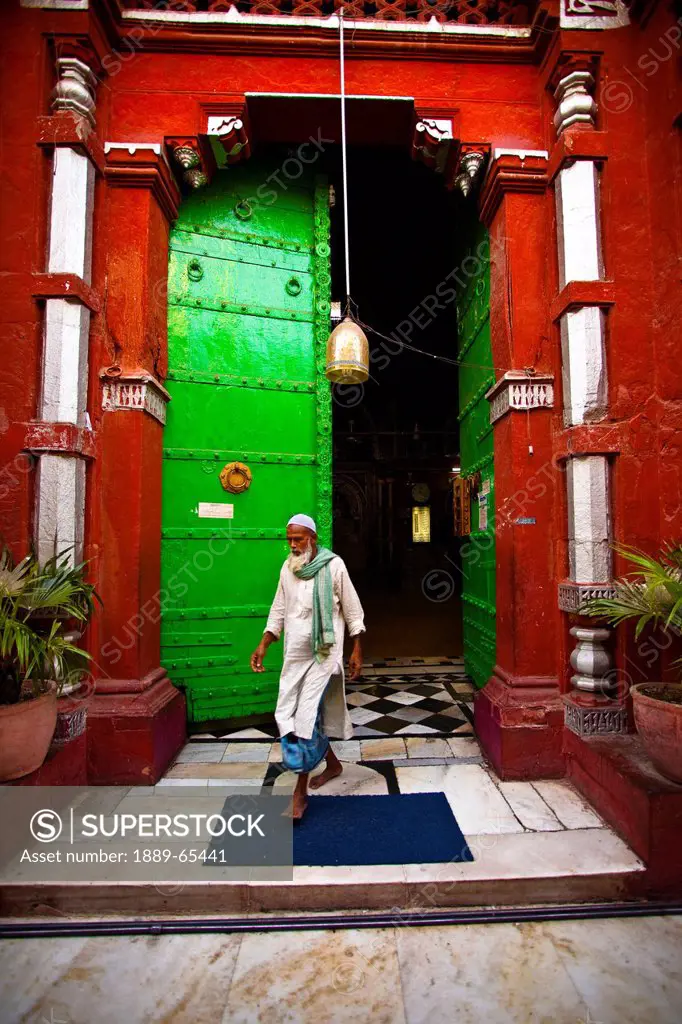 A Man Walks Out Of A Mosque With A Green Door And Red Walls, Delhi India