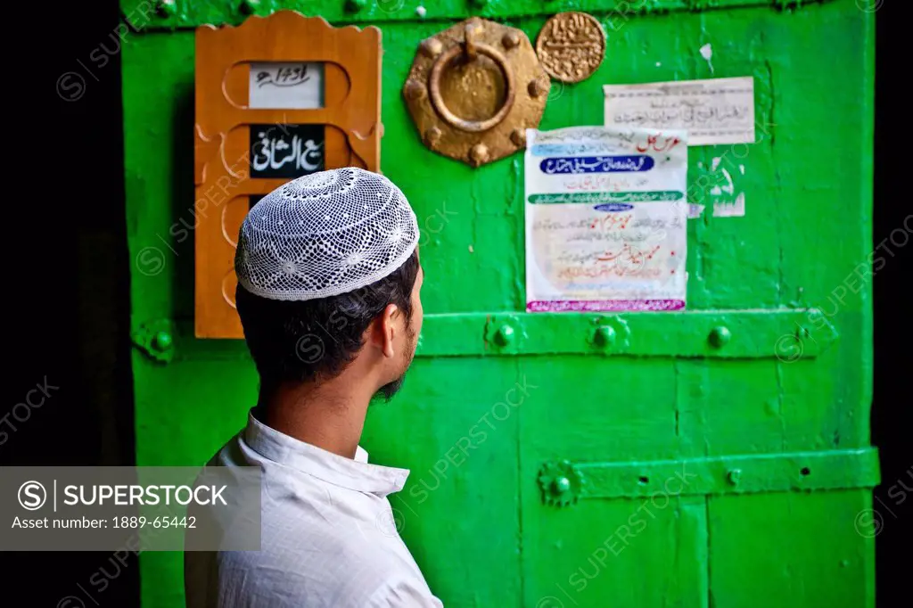A Man Read Postings On The Door To The Allauddin Masjid In Nizamuddin, Delhi India
