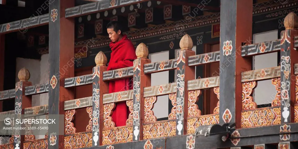 monk on balcony at trongsa dzong, trongsa district bhutan