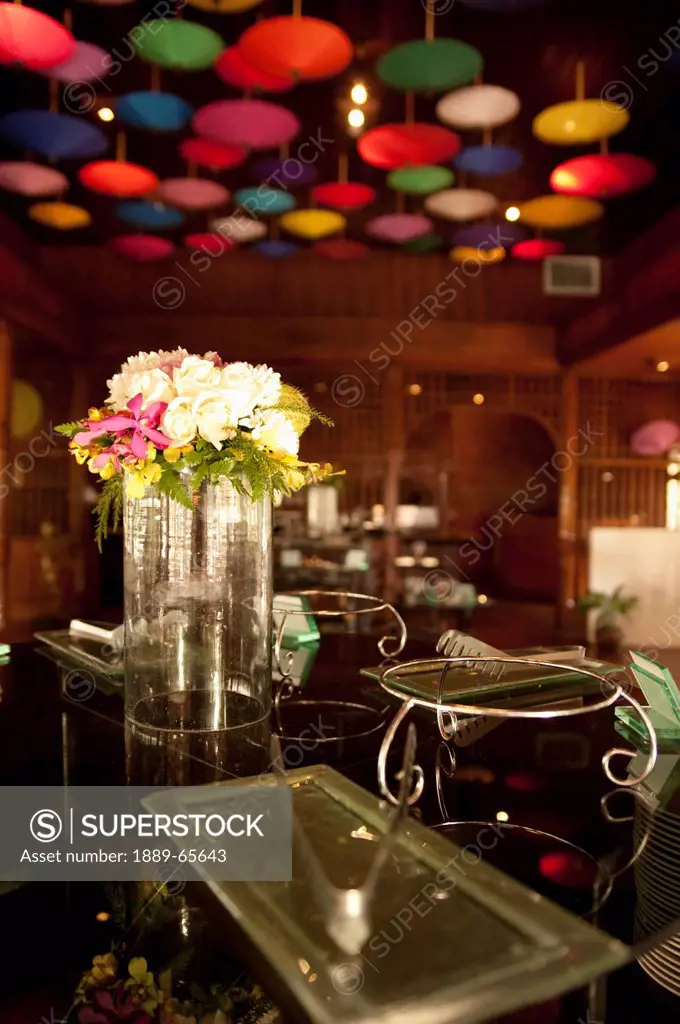 umbrellas hanging from the ceiling and a flower vase on the bar at the restaurant in amari rincome hotel, chiang mai thailand