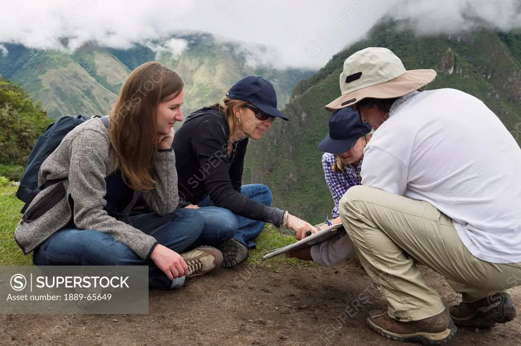tourists read from a guide at the lost city of inca, machu picchu peru