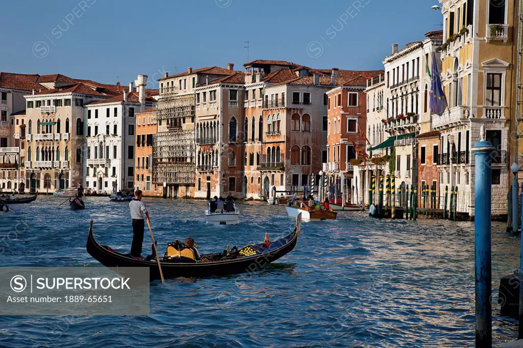 a gondolier and passengers in a gondola on the grand canal, venice italy