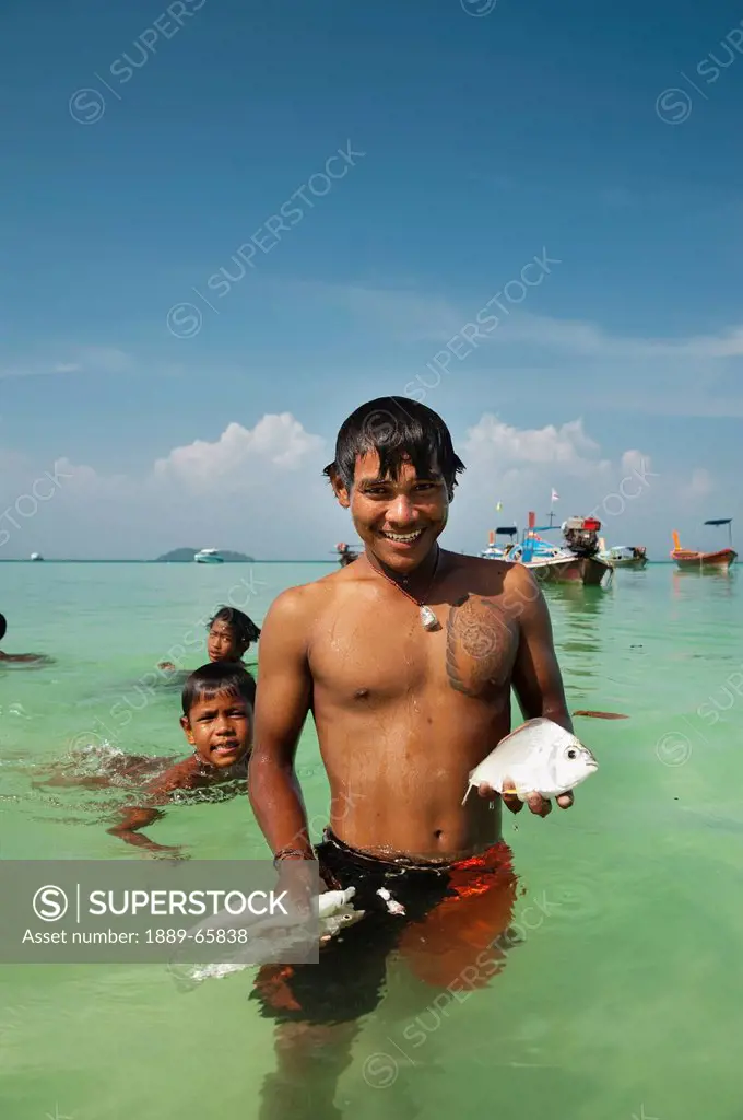 young man with fish in the ocean, phi phi islands thailand