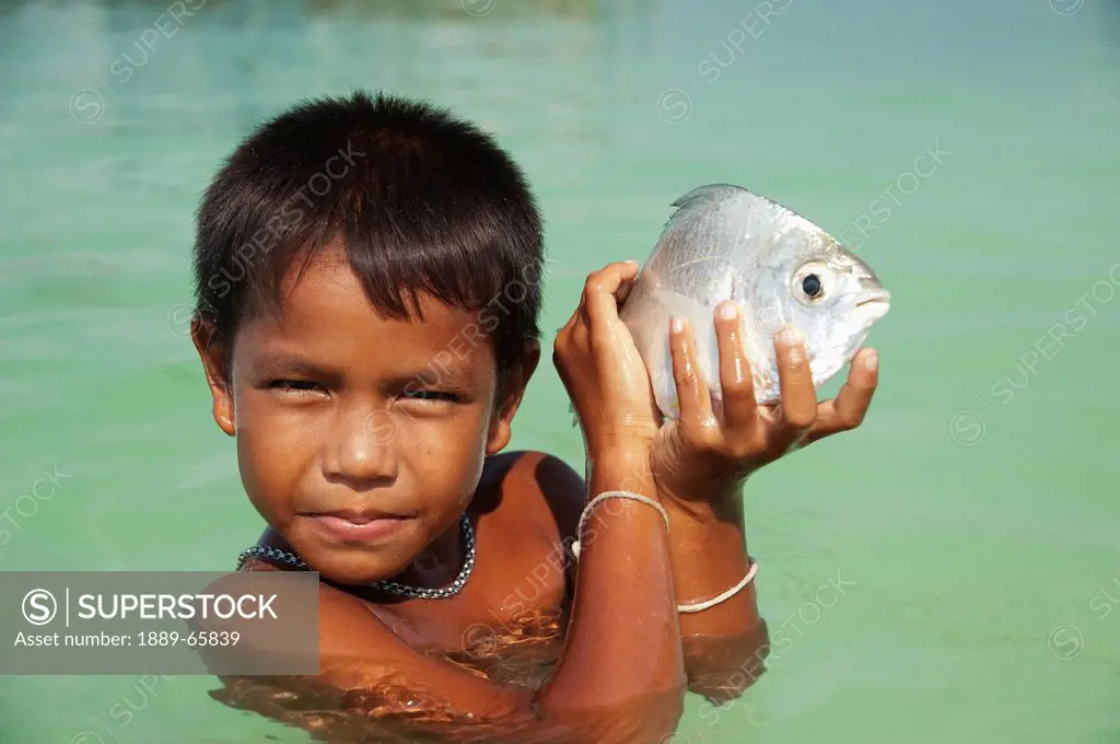 gypsy boy playing with fish in the sea, phi phi islands thailand