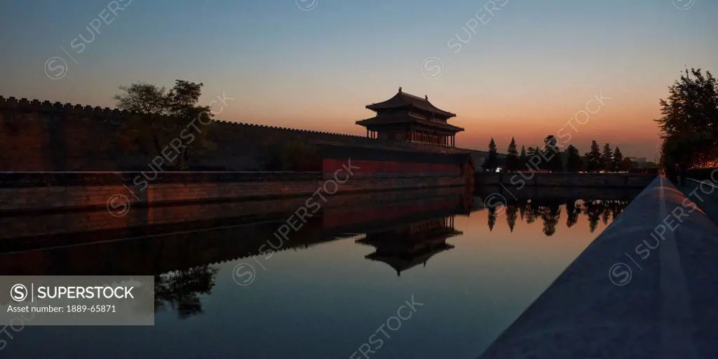 sunset over the moat at gate of divine might in forbidden city, beijing, china
