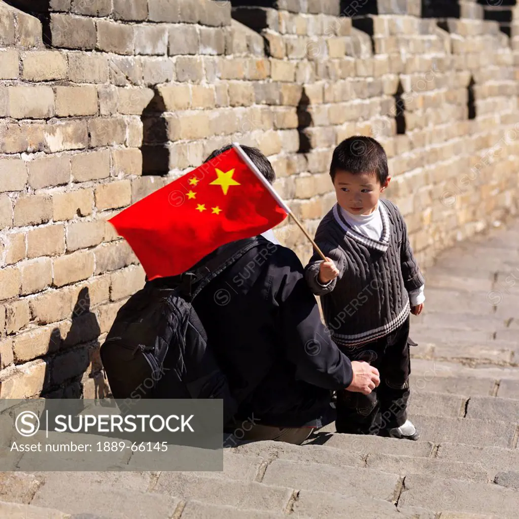 adult and child with chinese flag on the great wall of china, beijing, china