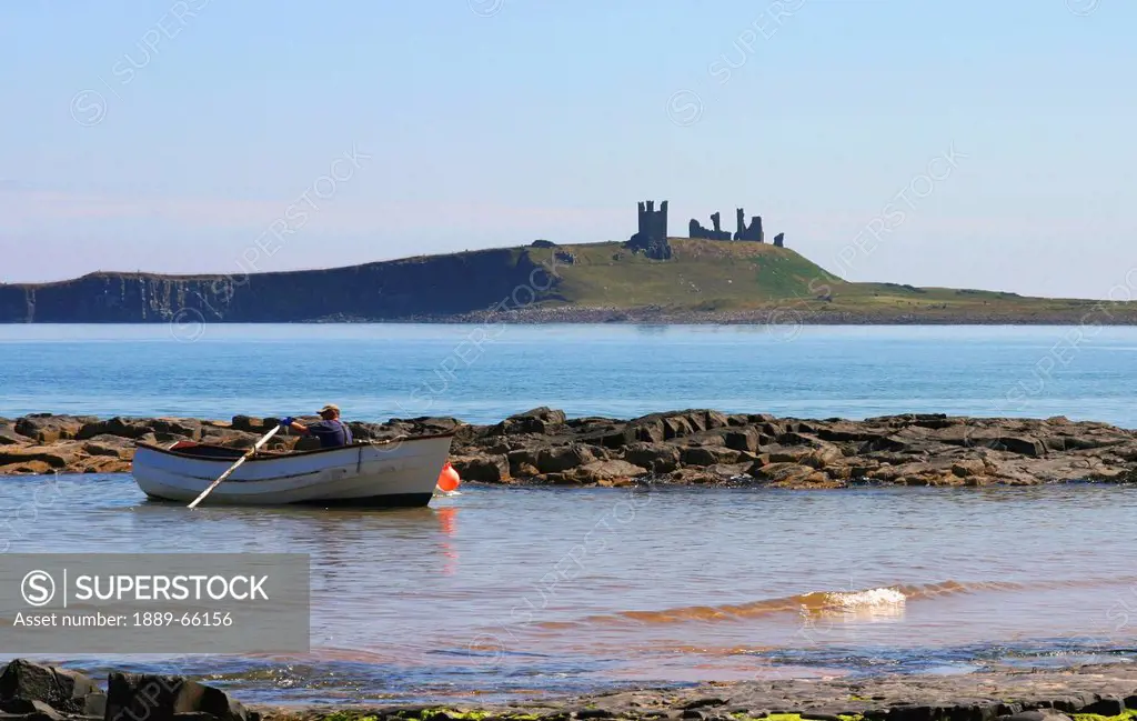 fishing boat and dunstanburgh castle, northumberland, england