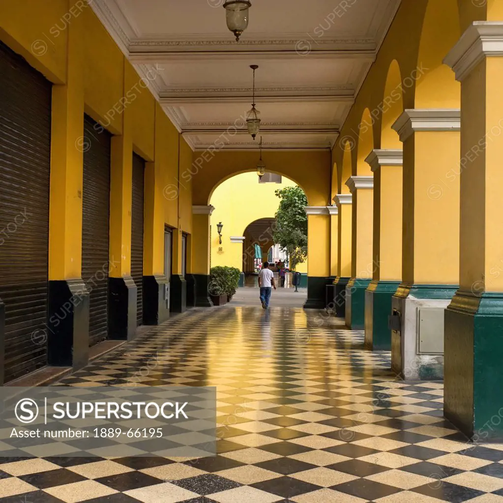 a man walks down the corridor in the historic centre of lima, lima peru