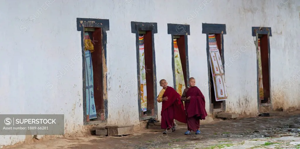 two novice monks walking in gangte goemba monastery, bhutan