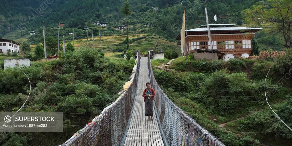 a woman walking on a suspension bridge, punakha district bhutan