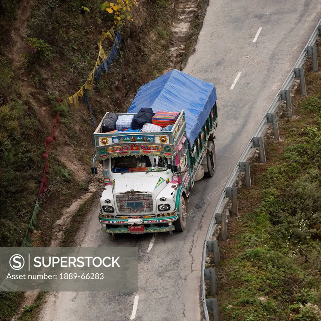 a truck covered with a tarp traveling on a road, thimphu district bhutan