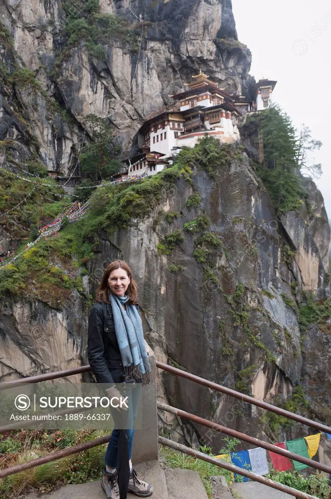 a woman standing at the top of steps at tiger´s nest monastery, paro district bhutan