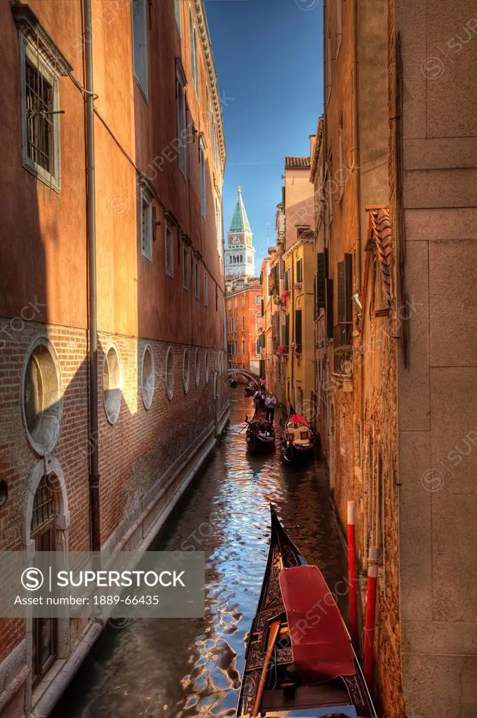 gondolas in a narrow canal between buildings, venice italy