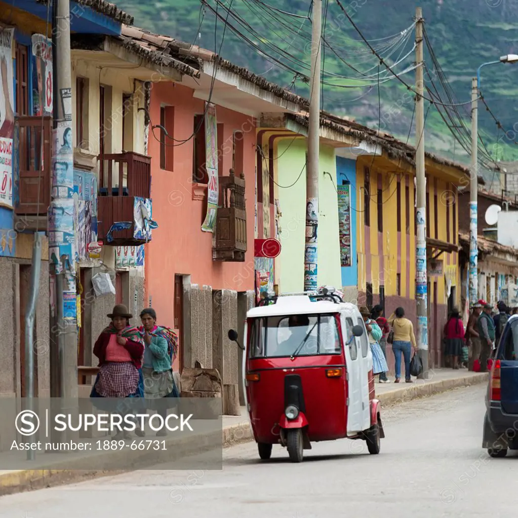 People Walking On The Sidewalk And A Motorized Vehicle Traveling Down The Street, Cusco Peru