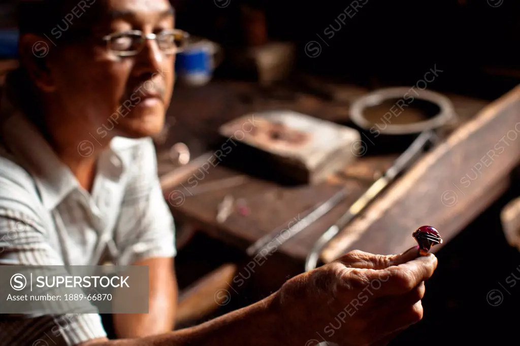 A Penesak Jeweler Holds Up A Ring For Inspection, Tanjung Batu Sumatera Selatan Indonesia