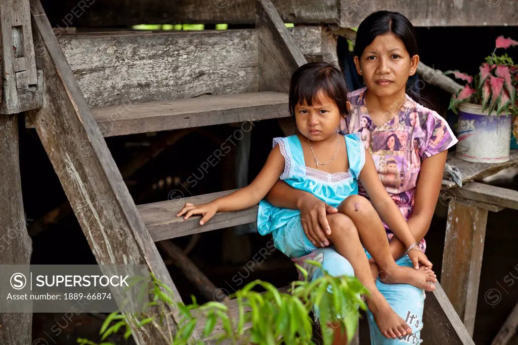A Mother Holds Her Daughter On Her Lap While Sitting On Wooden Steps, Sumatra Indonesia