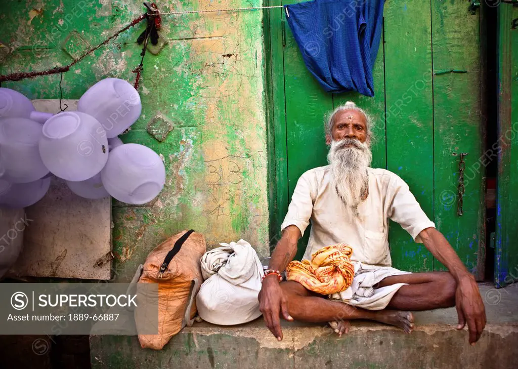 A Man Sits Cross Legged On A Concrete Step, Haridwar India