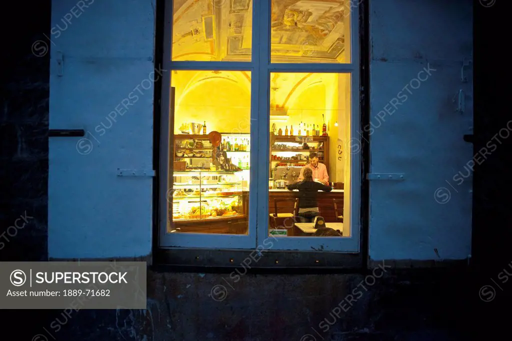 View Through The Window Of A Man Sitting At A Bar At Night, Genoa Liguria Italy