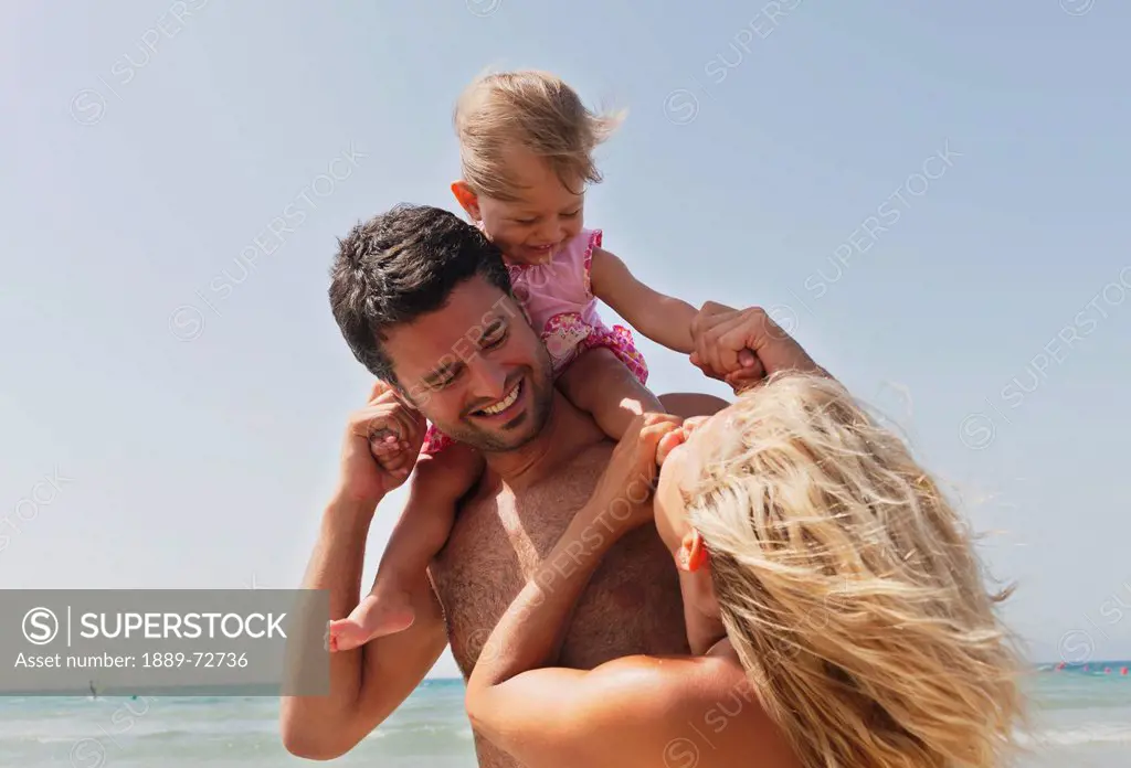 a mother and father on the beach with their young daughter, tarifa cadiz andalusia spain